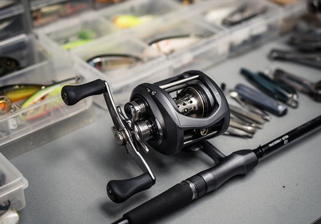 Left-hand retrieve baitcasting reel and matching rod laid out on a tackle counter with polished metal detailing