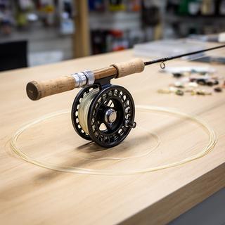 Three-weight fly rod and matched reel arranged on a wooden counter with pale leader line